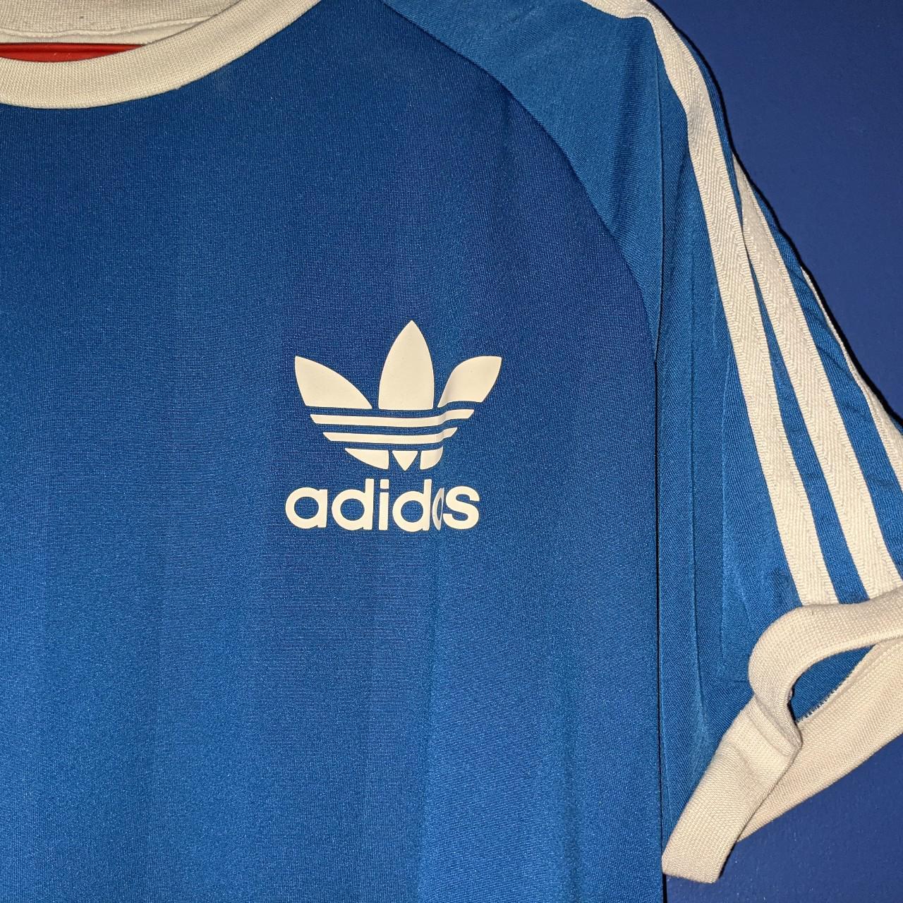 Blue Adidas Top with white emblem and white stripes... - Depop