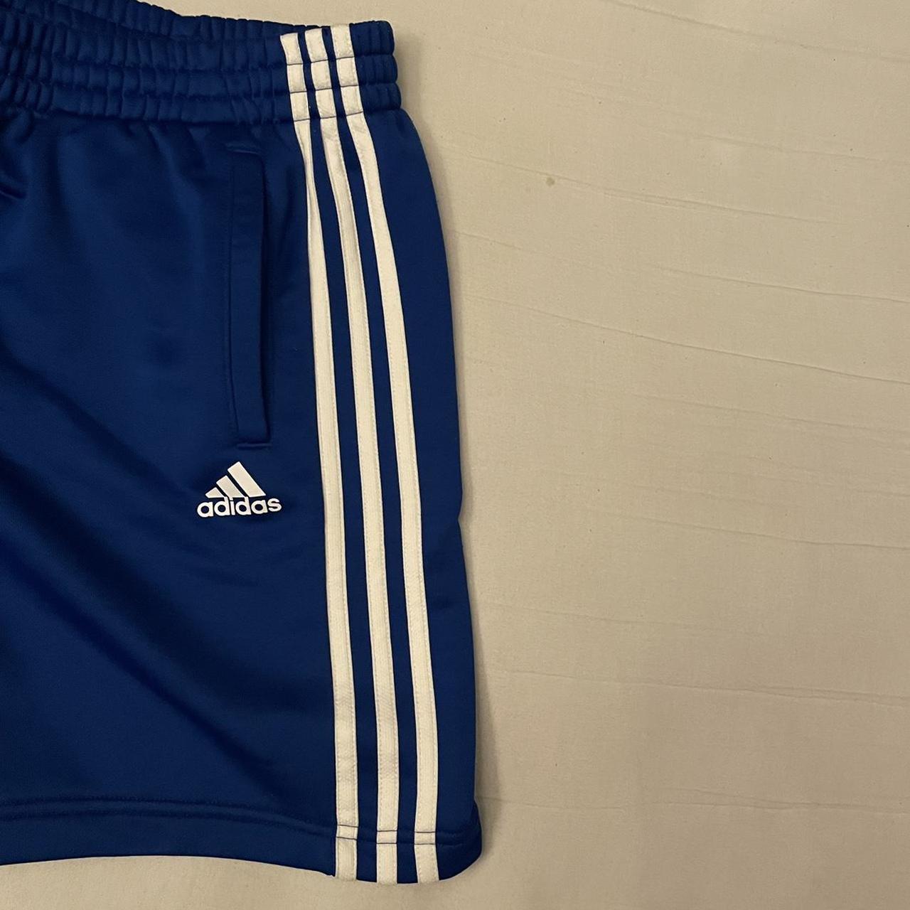 Blue Adidas shorts with three white stripes along... - Depop