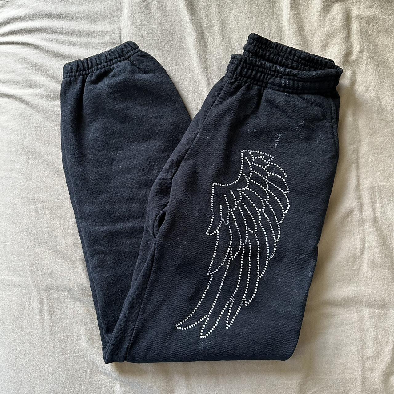 angel wing bedazzled black sweats. very much giving