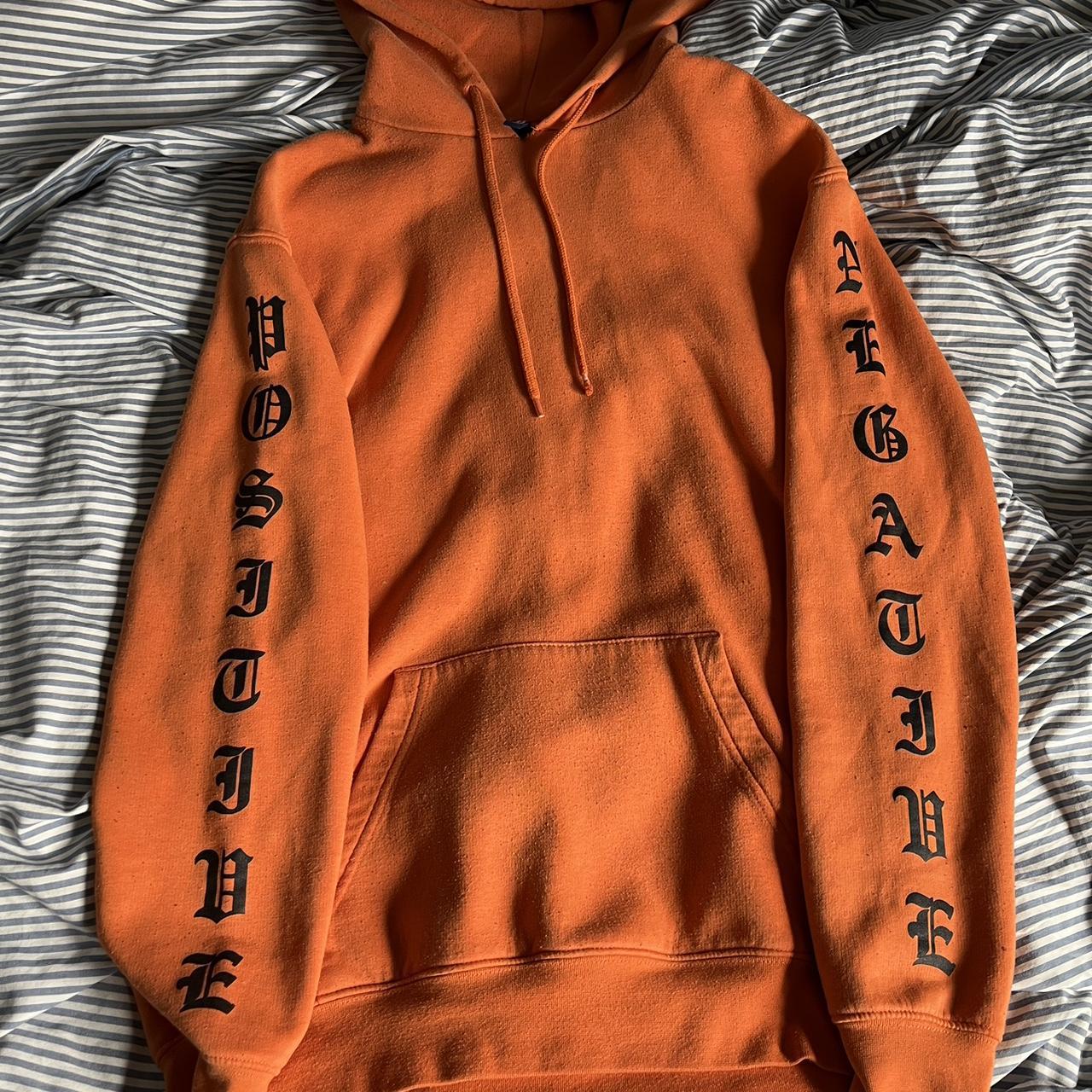 Orange hoodie with text on the sleeves and hood. In