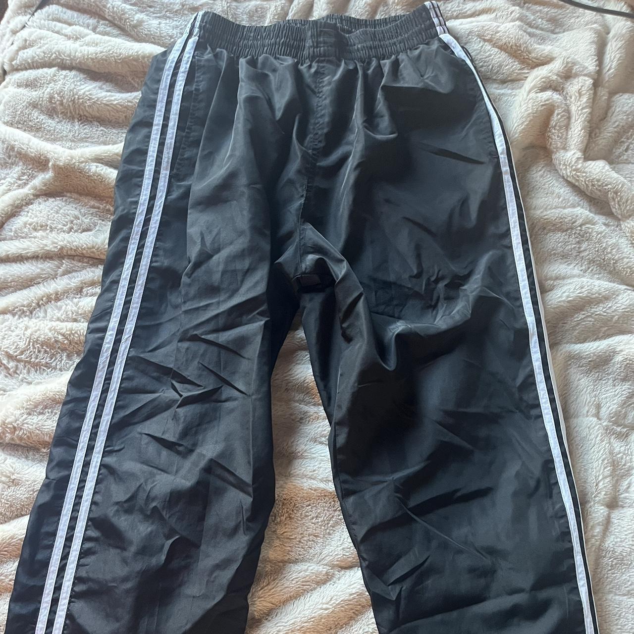 size large black track pants with two white stripes... Depop