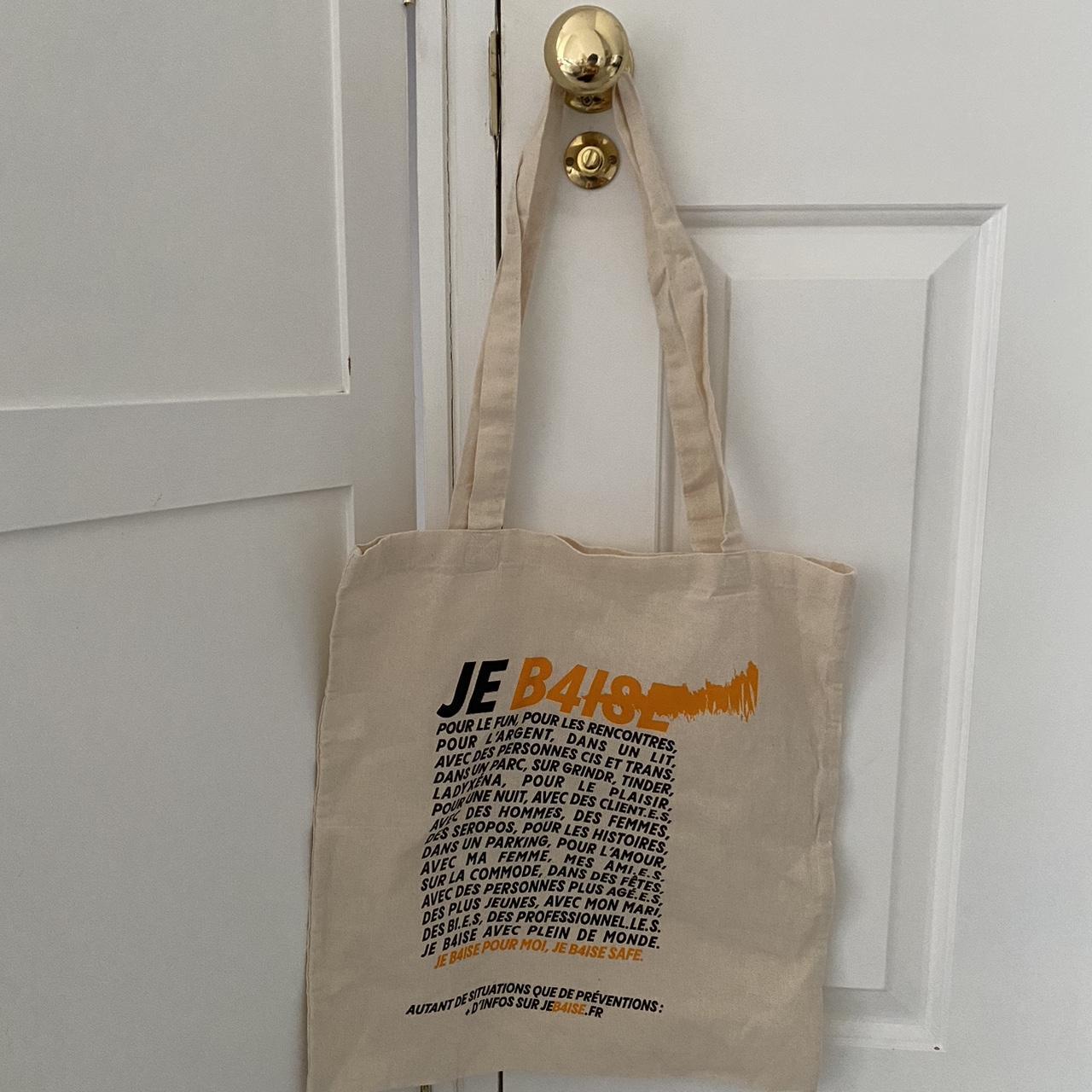 Cream tote bag with orange and black text in french - Depop